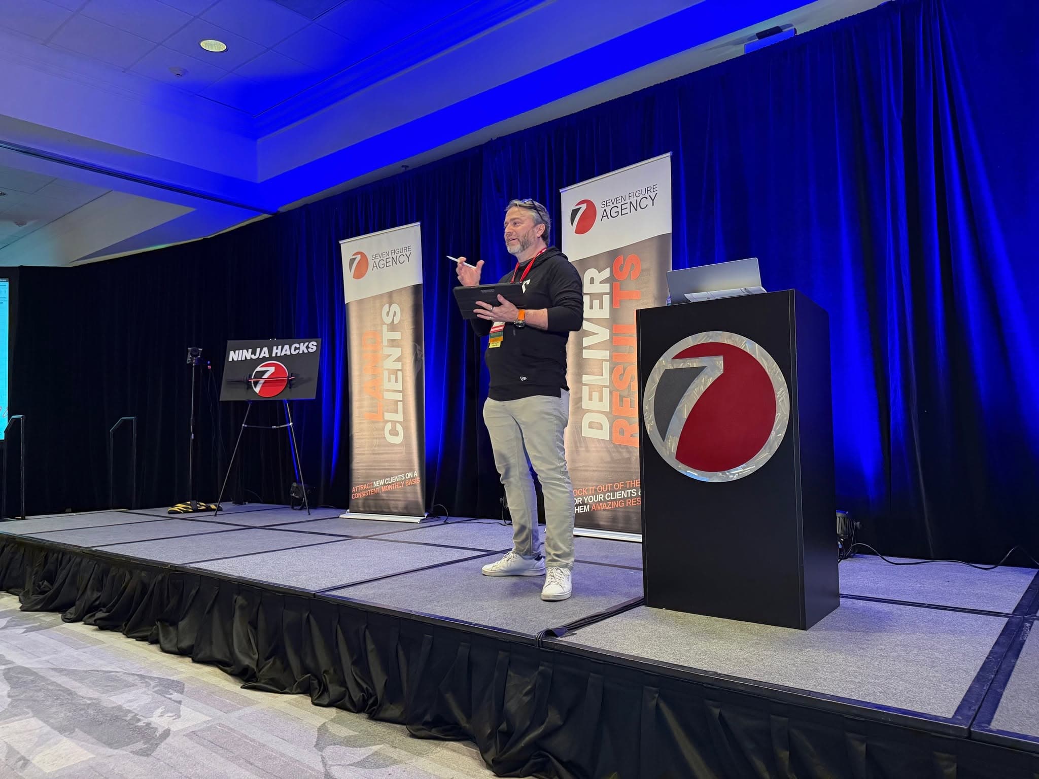 Lyn Askin speaking on stage at a business conference